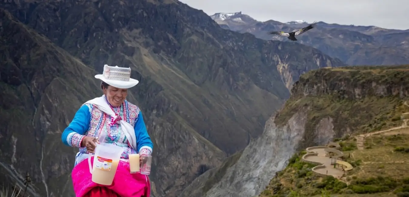 Pobladora del Cañón del Colca compartiendo la tradicional chicha, mientras un cóndor sobrevuela el cielo andino.