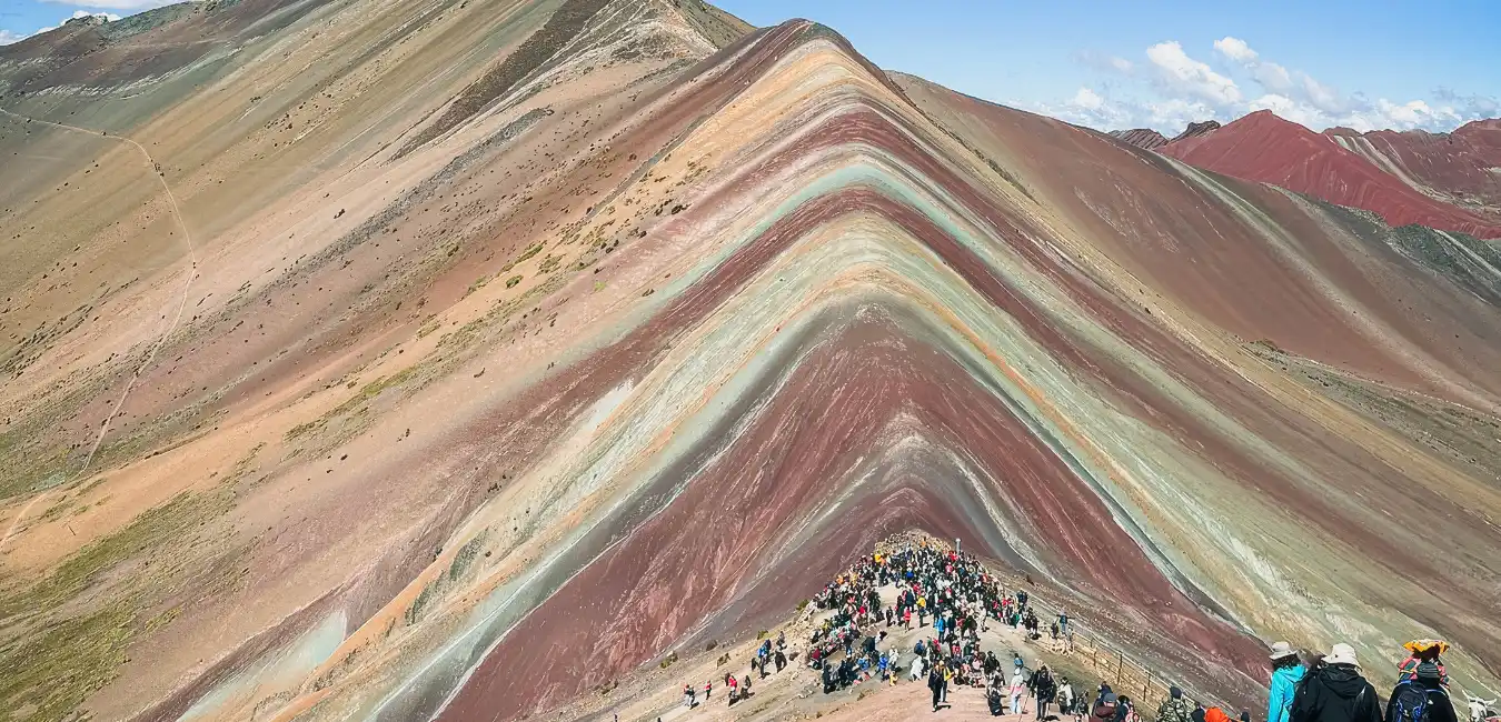 Rainbow Mountain surrounded by snow-capped peaks 