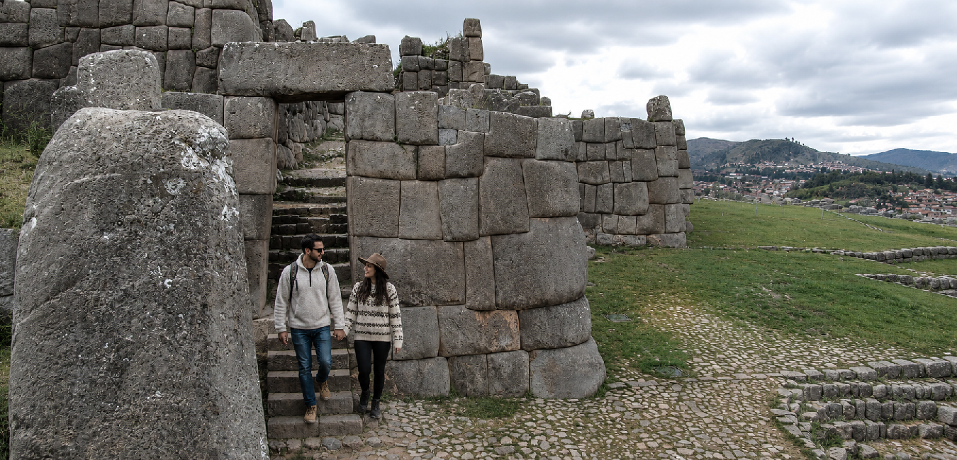 Travelers walking through the massive stone gateway at the Sacsayhuamán archaeological site overlooking Cusco, Peru.