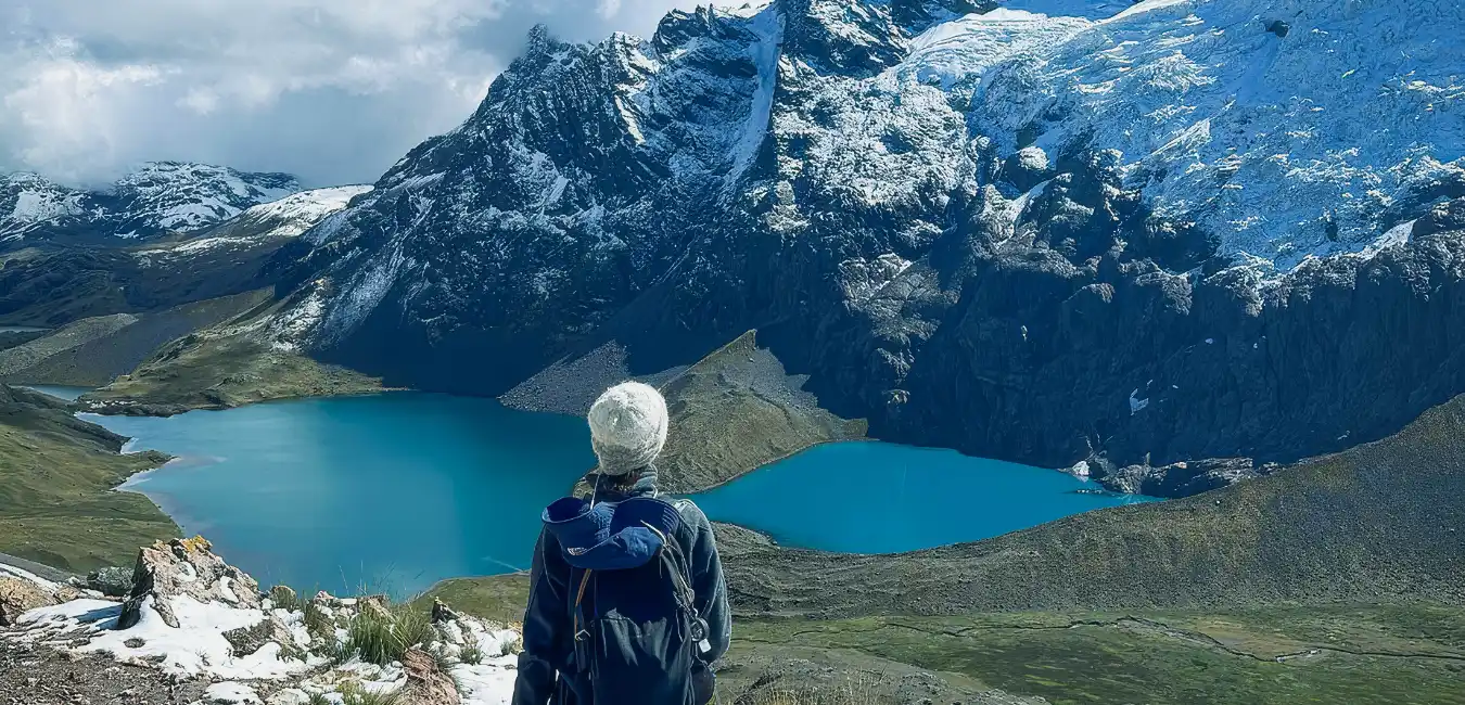 Traveler enjoying a turquoise glacial lake surrounded by the snow-capped Ausangate Mountains during the Ausangate Trek 